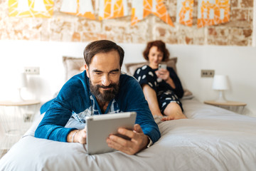 Couple relaxed at home in bed on the mobile phone and tablet.