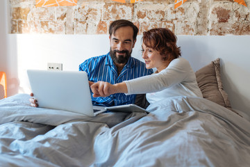 Couple relaxed at home in bed on the computer and tablet