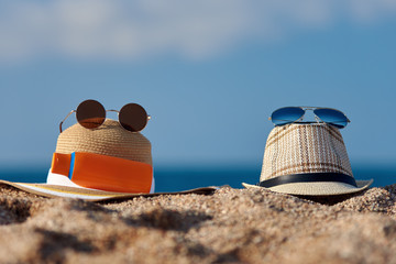Sunglasses, sunhats and sunscreen bottle against the sea.