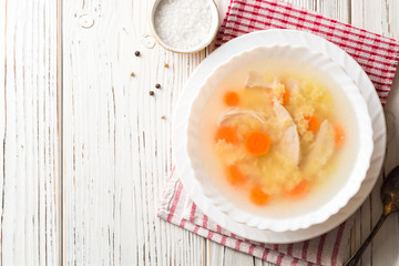 Chicken soup with stelline pasta and carrot on white wooden table.