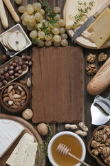 Creamy brie and camembert cheese with baguette and various nuts on rustic wooden background. Top view, close-up, space for text