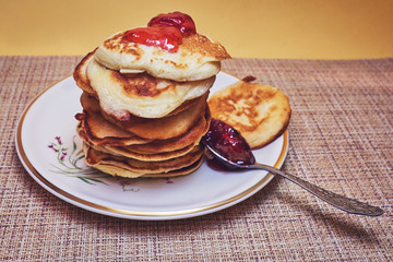 A pile of pancakes with jam and a spoon