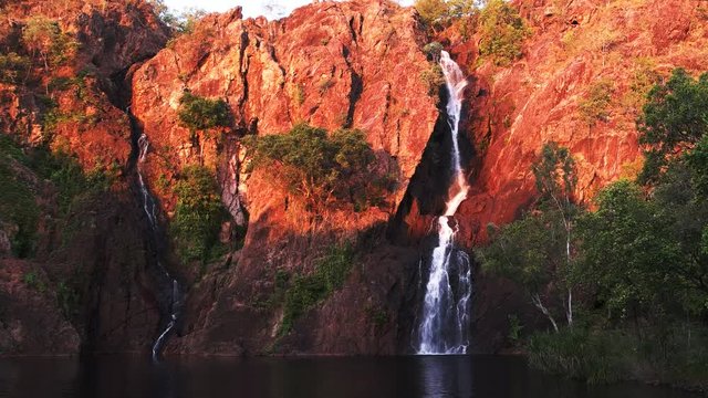 the setting sun turns the cliffs at wangi waterfalls in litchfield national park a brilliant red