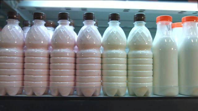 Sour-milk products in the supermarket.
Horizontal pan.
The camera moves along the shelf on which are bottles of milk and dairy products.