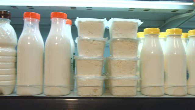 Sour-milk products in the supermarket.
Horizontal pan.
The camera moves along the shelf on which there are cottage cheese, milk, kefir and yogurt.