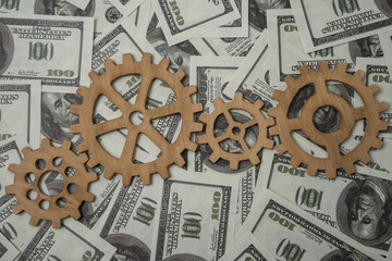 gears are connected in a puzzle for movement, money background is a dollar banknote. Business...