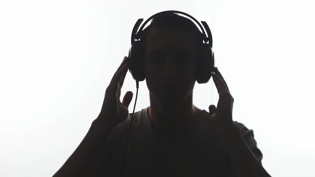 Silhouette of Man putting on headphones and listening music isolated on white background