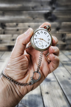 Adult man holding an antique pocket watch in his hand