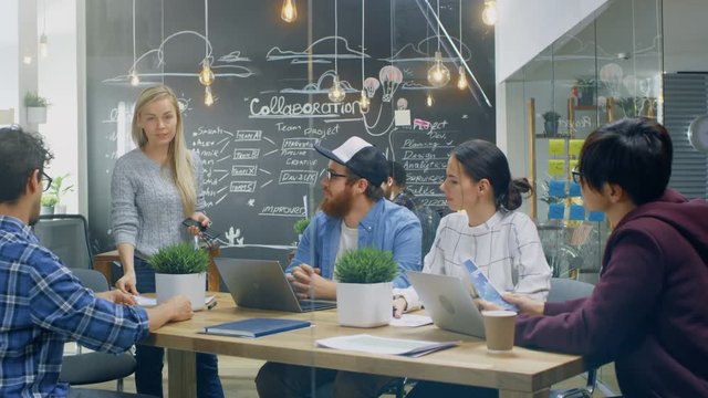 Female Team Leader Speaking at the Group Meeting, Discussing Company's Aims, Ambitions and Future Projects. Creative Young  Developers in the Trendy Office Environment. 