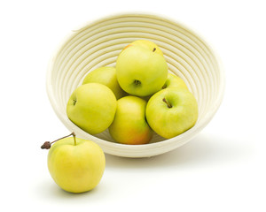 Apples (Smeralda variety) in a rattan bowl isolated on white background green yellow.