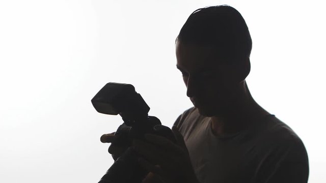 Silhouette of Photographer close-up. Young man takes pictures with DSLR camera isolated on white background