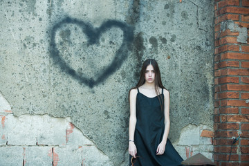 Girl posing with heart graffiti on grey wall