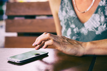 Woman using her smartphone  outside. Woman sitting in restaurant and writes messages on her cell phone. 