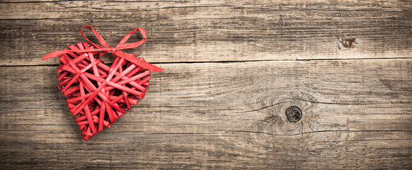 Red wicker heart on wooden background