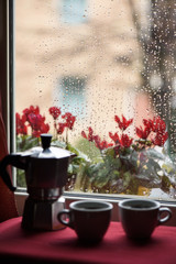 Cups of Hot Coffee and Espresso Machine in front of window raindrops