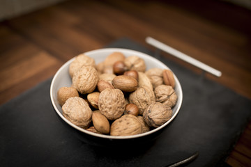 A bowl of mixed whole nuts in their shells including walnuts, hazelnuts, almonds and pecans with a short depth of field