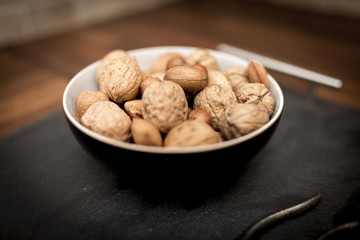 A bowl of mixed whole nuts in their shells including walnuts, hazelnuts, almonds and pecans with a short depth of field