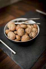 A bowl of mixed whole nuts in their shells including walnuts, hazelnuts, almonds and pecans with a nut cracker