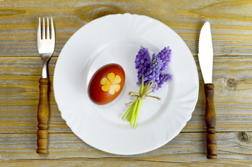 Easter table decoration: Easter egg colored naturally and spring flowers on the plate