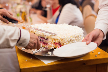 Closeup pf hands cutting the cake