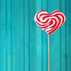 Heart shaped lollipop for Valentines Day turquoise background