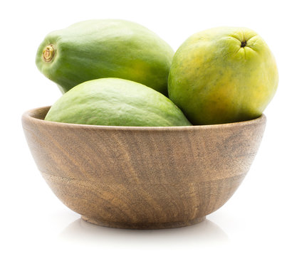 Green papaya (pawpaw, papaw) in a wooden bowl isolated on white background.