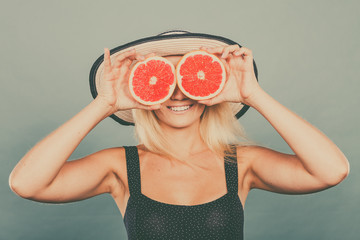 Woman holding red grapefruit fruit like eyeglasses