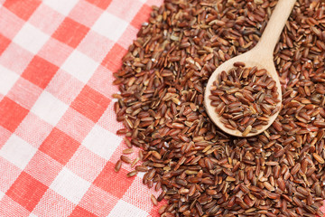 Top view of wooden spoon with red rice, close-up