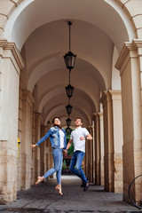 a couple in love jumping on the background of the building with arches and lanterns