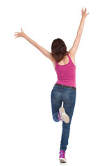 Young Woman Is Standing On One Leg With Arms Raised. Rear View.