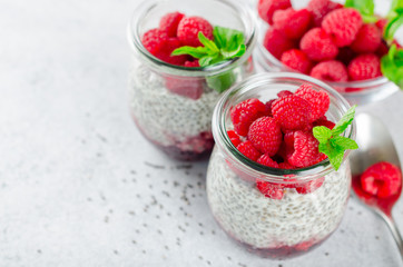 Two glass jars with chia pudding with raspberry and jam. Bowl of