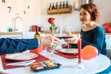 Mature couple having a romantic dinner at home for valentine’s day and doing toast with red wine .