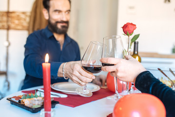 Mature couple having a romantic dinner at home for valentine’s day and doing toast with red wine .