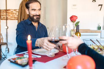 Mature couple having a romantic dinner at home for valentine’s day and doing toast with red wine .
