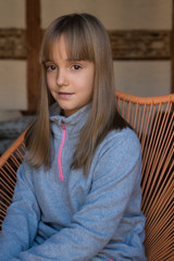Portrait of a young cute little blonde girl sitting in the chair .