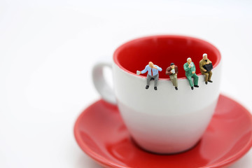 Miniatures people : sitting on a cup of coffee using as background business concept.