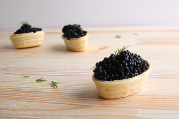 black caviar tartlet wooden background