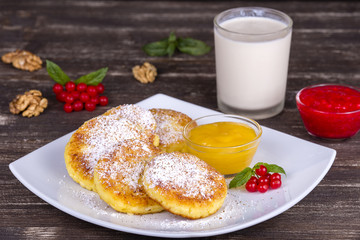 Cottage cheese pancakes, homemade syrniki with honey in white plate.