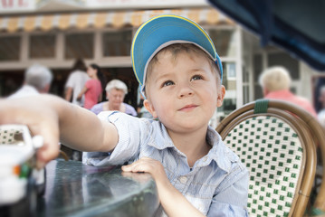 People, handsome boy of two years with a toy, in a cafe at a table in anticipation of an ice cream