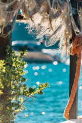 Old Fishnet Hanging on wooden construction at the Sunny day near the sea.