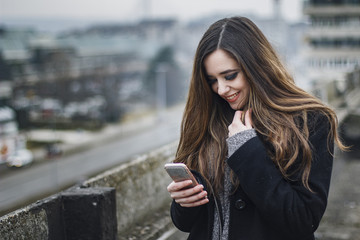 Fototapeta premium Beautiful young woman reading a happy text she gets on her smartphone