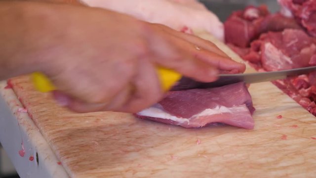 Butcher cutting pork meat on the table. Slow moton, close-up. 