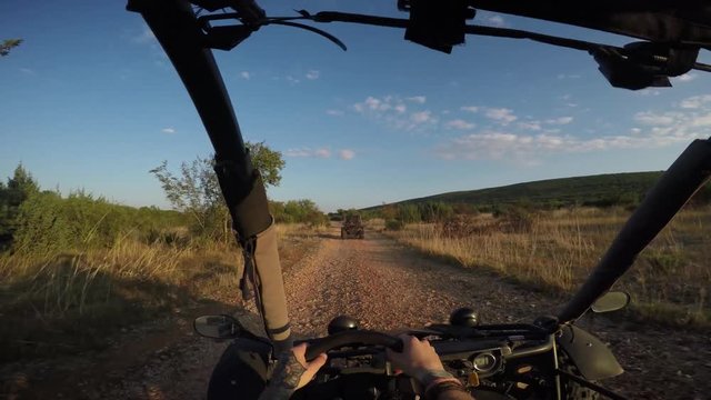 gopro shot of young man driving dune buggy in the sunset on a dirtroad