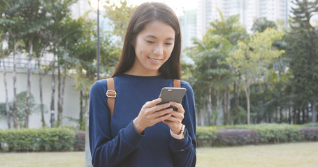 Fototapeta premium Young woman use of mobile phone in city park