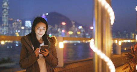 Woman use of mobile phone in the city at night