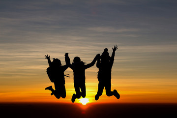 Fototapeta na wymiar Happy three young girls with backpack jumping at sunrise or sunset time.
