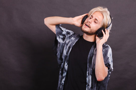 Blonde man singing in studio wearing headphones