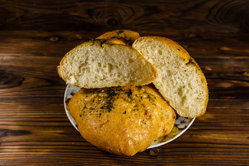 Plate with italian bun ciabatta on wooden table. Top view