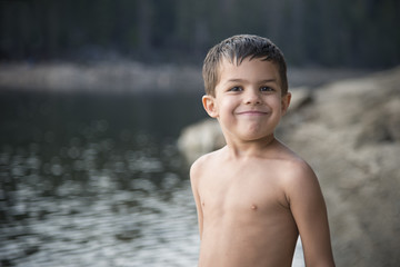 Smiling, shirtless, adorable little boy after swimming at mountain lake