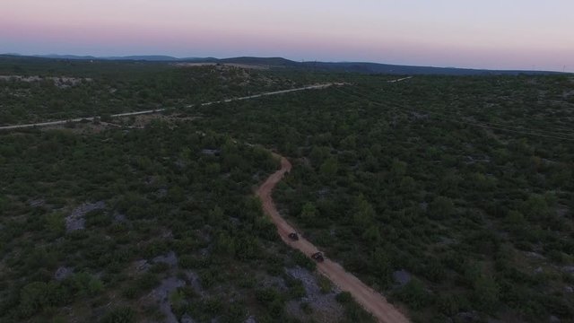 Drone shot of dune buggies driving offroad on a dirt road in the dark